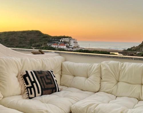 a white couch sitting in front of the beach at Santa Rita Sunset & Beach Apartment in Maceira