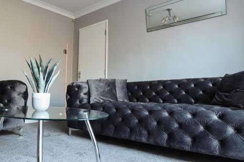un sofá de cuero negro en una sala de estar con mesa de cristal en The Grey Haven Birmingham, en Birmingham