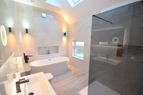 a bathroom with a white tub and a sink at Modern luxury home in Wallasey