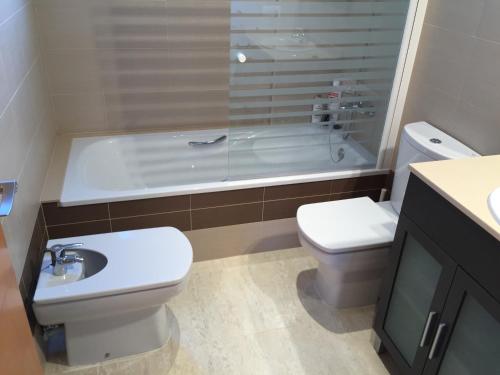a bathroom with a toilet and a tub and a sink at Turó de Tjelle in L'Ampolla