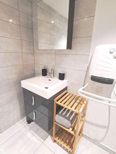 une salle de bain blanche avec un lavabo et un miroir dans l'établissement Loft proche des plages et sites du débarquement, à Osmanville