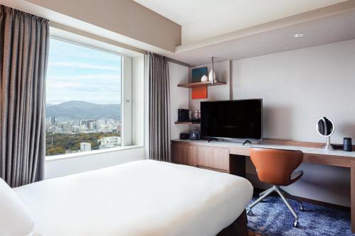 a hotel room with a bed and a desk and a window at ANA Crowne Plaza Hiroshima, an IHG Hotel in Hiroshima