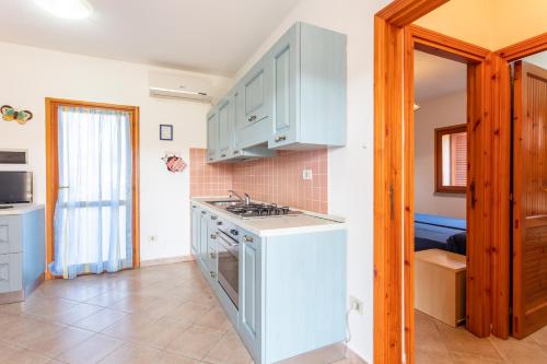 a kitchen with white cabinets and a stove top oven at La Basoledda in Isola Rossa
