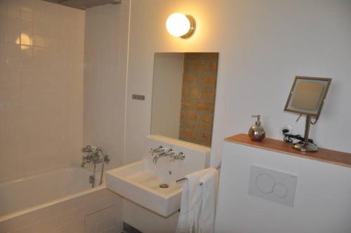 ein Bad mit einer Badewanne und einem Waschbecken sowie einen TV in der Unterkunft Maison Le Corbusier in Doncourt-lès-Conflans