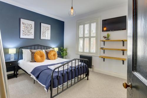 a bedroom with blue walls and a bed with orange pillows at 2 Bedroom Terrace House in Bedford by SILVA in Bedford