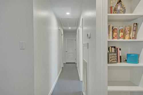 a hallway with white walls and a staircase with books at The Nathalie - curated, open, tree covered family in Charleston
