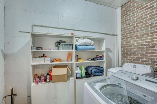 a laundry room with a washing machine and a brick wall at The Nathalie - curated, open, tree covered family in Charleston
