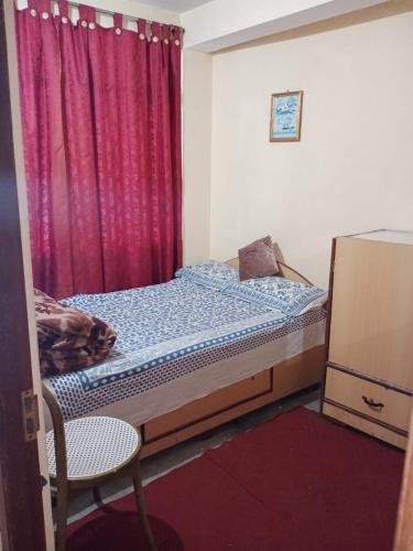 ein kleines Schlafzimmer mit einem Bett und einem roten Vorhang in der Unterkunft Benus in Darjeeling