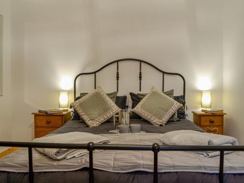 Willesdene Cottage في Abernethy: غرفة نوم بسرير ومخدات ومصباحين