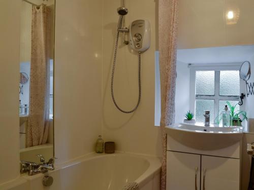 a bathroom with a shower and a tub and a sink at Willesdene Cottage in Abernethy