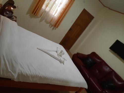 a bedroom with a bed with white sheets and a window at Binalonan Transient/GUESTHOUSE (PENSION GLAYDIE) in Binalonan