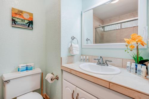uma casa de banho com um lavatório, um WC e um espelho. em Sandpiper #105b em Princeville