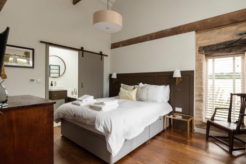 um quarto com uma grande cama branca e uma secretária em Linseed Barn- Stamford Holiday Cottages em Stamford