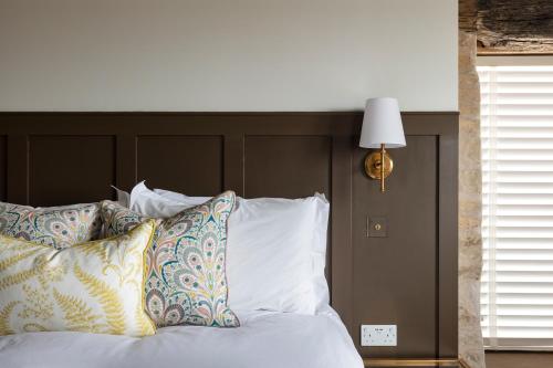 a bed with white pillows and a brown headboard at Linseed Barn- Stamford Holiday Cottages in Stamford