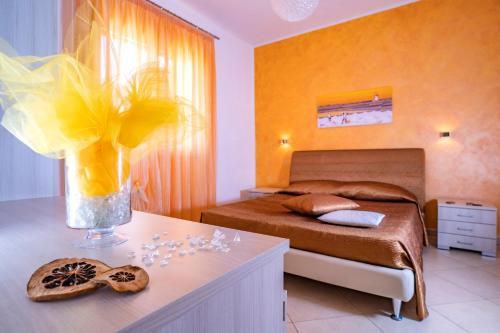 um quarto com uma cama e um vaso de flores sobre uma mesa em B&B Pietre Preziose em Castelluzzo