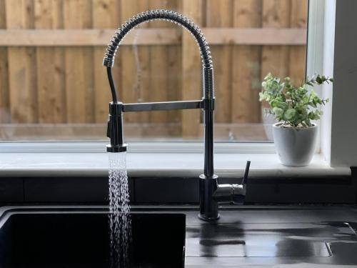 a kitchen sink with water pouring from a kitchen faucet at Holdsworth House Apartments in Killingbeck