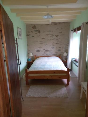 a bedroom with a bed and a stone wall at Les Deux Sapins in La Châtre-Langlin