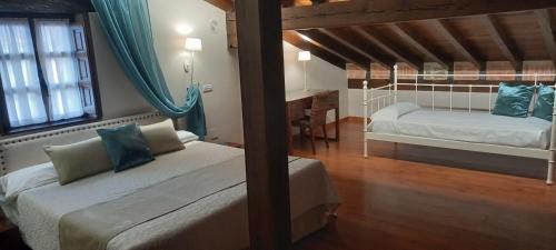 1 dormitorio con 2 camas y escritorio. en La Casona de Revolgo, en Santillana del Mar