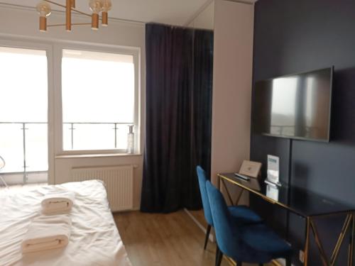 una camera con letto, scrivania e TV di Warsaw To Be - Blue Apartment a Varsavia