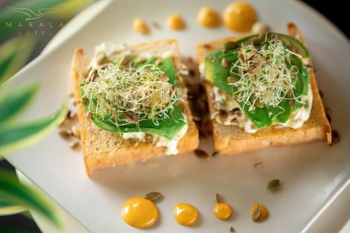 a white plate with two slices of bread with greens and seeds at Marala Hotel in Esterillos