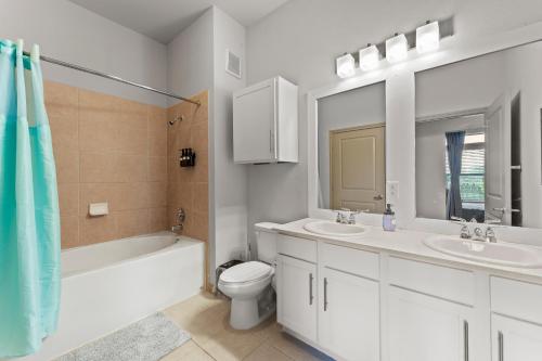 a bathroom with two sinks and a toilet and a mirror at Spacious 2BR King Bed Suites Close to Downtown and Airport in Austin