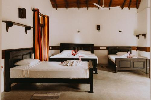 two beds in a room with two tables and two beds at Shiva's Beach Cabanas in Tangalle