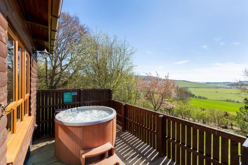 a hot tub on the deck of a house at Mountain Ash Lodge with Hot Tub in Cupar
