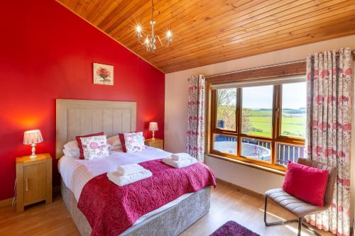 a bedroom with red walls and a bed and a window at Mountain Ash Lodge with Hot Tub in Cupar