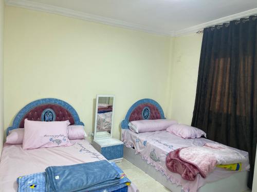 - une chambre avec 2 lits et un miroir dans l'établissement Gardenia city cairo, au Caire