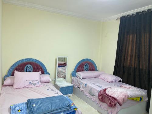 une chambre avec deux lits et un miroir dans l'établissement Gardenia city cairo, au Caire