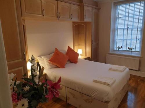 a bedroom with a large white bed with orange pillows at Beautiful 2 Bedroom Flat in Frampton Street in London