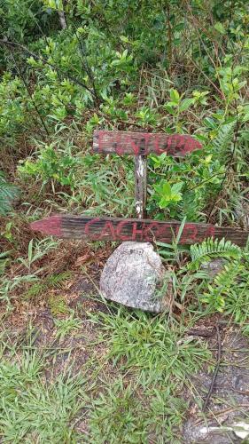 a sign in the grass next to a rock at Pouso do Elefante in Serra do Cipo