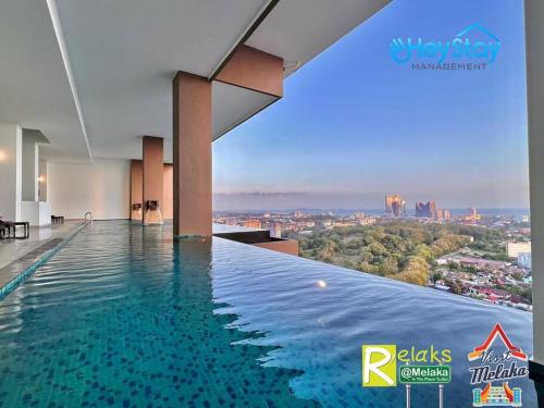 a swimming pool in a building with a view of a city at The Apple Residence By Heystay Management in Melaka