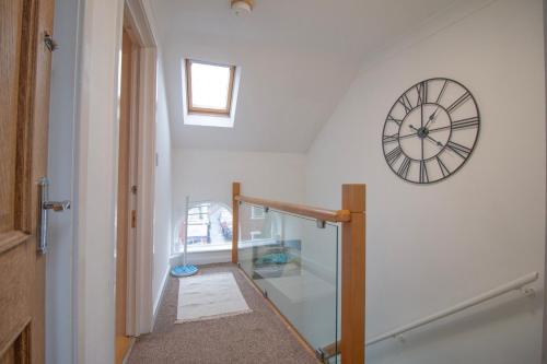 a stairway with a clock on a white wall at Sealock Mews by Property Promise in Cardiff