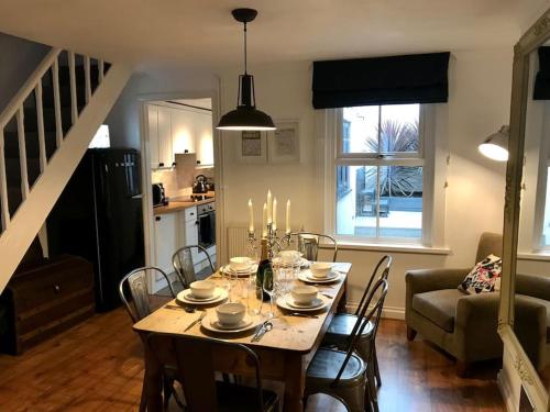a dining room with a table with chairs and a kitchen at Spa Cottage Weymouth in Weymouth