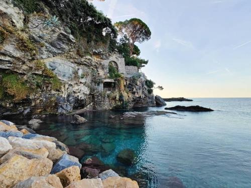 a rocky shore with clear blue water and rocks at La Casa di Milly in Sori