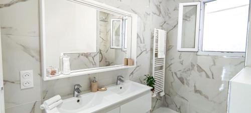 a white bathroom with a sink and a mirror at Villa Palmire, large terrace with jacuzzi available in La Turbie