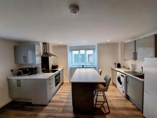 una cocina con armarios blancos y una mesa. en Apartment Balmoral Road en Northampton