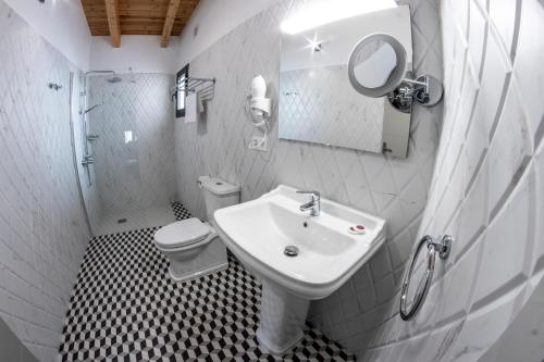 a bathroom with a sink and a toilet and a mirror at Hotel Rural La Casa de Carlota in Montánchez