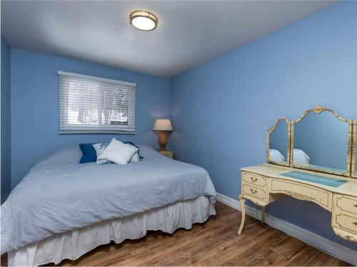 Dormitorio azul con cama y espejo en Cozy Escape, Kawarthas Cottage With Sauna, en Buckhorn