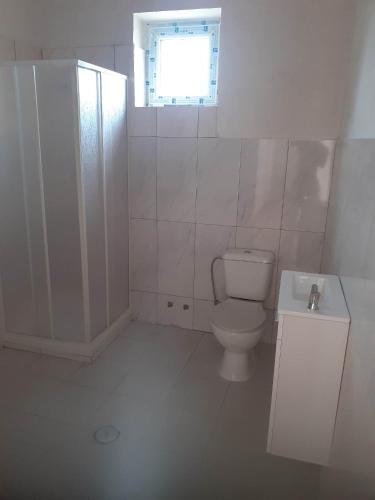 a white bathroom with a toilet and a window at VICTORIA HOSTEL in Canavial