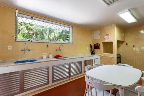 uma cozinha com mesa e cadeiras e uma janela em Aconchegante Sítio na Serra com piscina em Itaipava 26 hóspedes em Itaipava