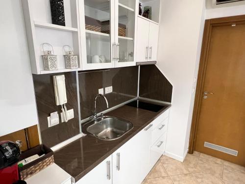 a kitchen with a sink and white cabinets at Eve Santa Marina Apartment II - sea, pools, relax in Sozopol