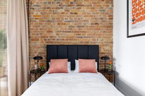 a bedroom with a brick wall and a bed with pink pillows at Apartament Aleja 22 in Poznań