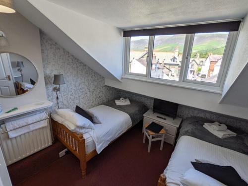 a small room with two beds and a window at Harvington House in Keswick