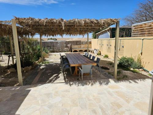 a wooden table and chairs sitting under a pergola at Loft Ardon in Mitzpe Ramon
