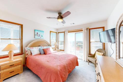 a bedroom with a bed and a tv and windows at Ocean Song #3-CA in Avon