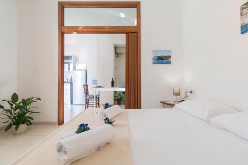 une chambre avec un grand lit blanc et une cuisine dans l'établissement Pearl Suite Apartment, à Cala Gonone