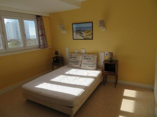 a bedroom with a bed and two windows at Maison de villégiature cote opale in Hardelot-Plage