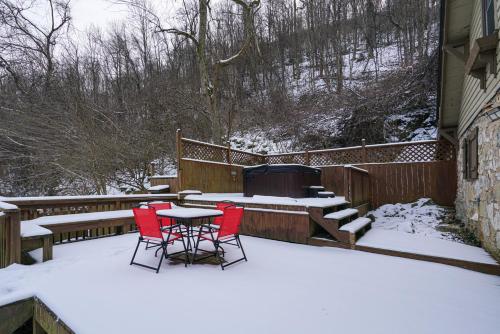 a patio with two red chairs and a table in the snow at River Front Resort in Elkins
